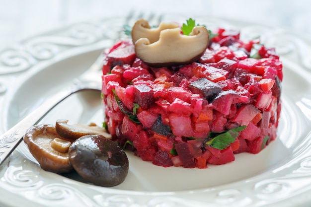 Russian salad with marinated mushrooms on a white plate