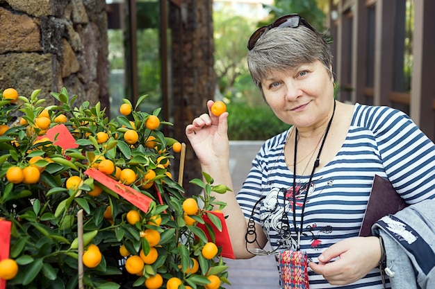 Russian tourist near Christmas tangerine tree Mandarin duck in his hand