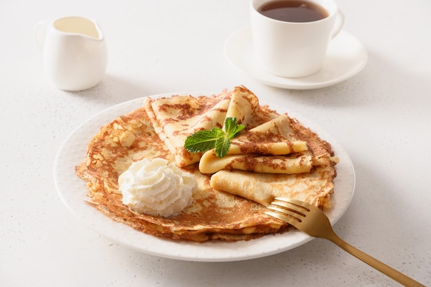 Russian traditional breakfast for Shrovetide of thin pancakes with whipped cream.