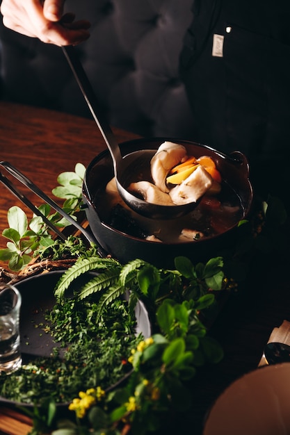 Russian traditional fish soup in a bowl  ukha served with ember and vodka on wooden board Fish broth Traditional cuisine in Russia