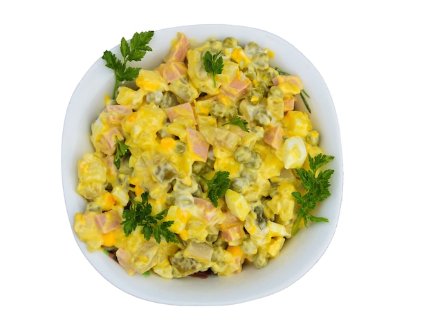 Russian traditional salad olivier with green pea, eggs, pickled cucumber, potato, sausages and mayonnaise isolated on white background. Top view