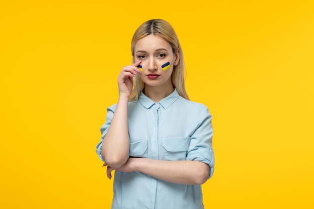Russian ukrainian conflict cute girl yellow background with ukrainian flag on cheeks crying