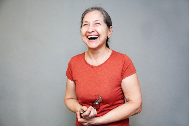 Русская женщина 55 лет смеется на сером фоне