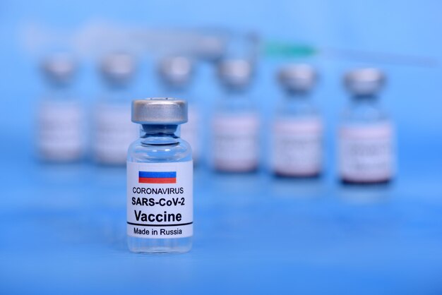 Russisch vaccin en medisch concept voor de gezondheidszorg. Vaccins en spuit op blauwe achtergrond voor preventie, immunisatie en behandeling van coronavirusinfectie