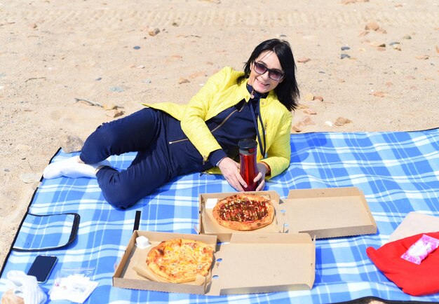 Russische 45-jarige vrouw gaat pizza eten terwijl ze op het strand zit