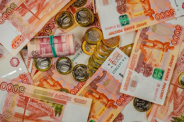 Russische bankbiljetten van 5000 roebel met munten op tafel.