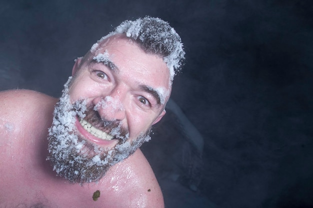 Russische extreme een naakte man in de sneeuw met bevroren baard en haar in de wolken van stoom