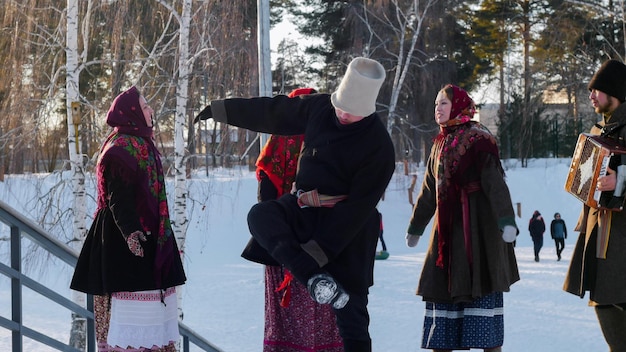 Russische folklore jonge mensen in vilten laarzen dansen buiten in de winter in het park