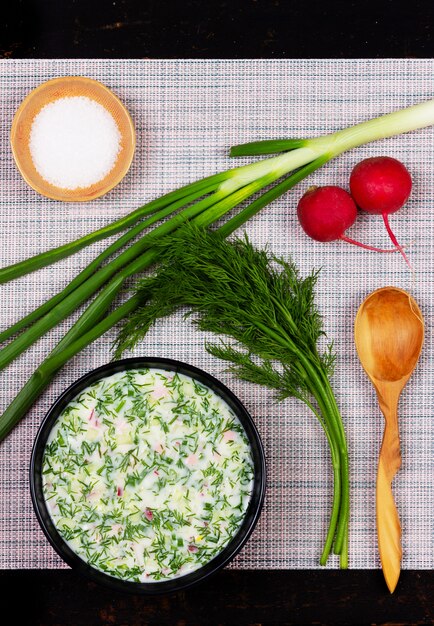 Russische okroshka van de de zomer koude soep van greens, groenten, kvass en kefir op de lijst