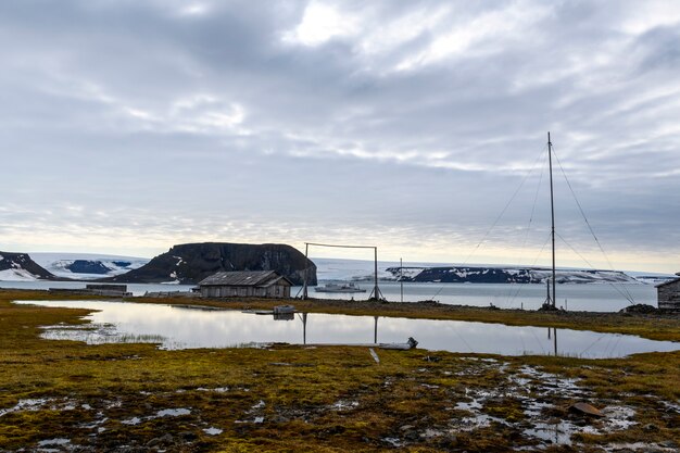 Foto russische onderzoeks- en poolexpeditiebasis in tikhaya bay (tikhaya bukhta) op de franz josef land-archipel. houten gebouwen in het noordpoolgebied.