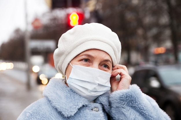 Russische oudere senior vrouw in medische beschermend masker in de winter op straat