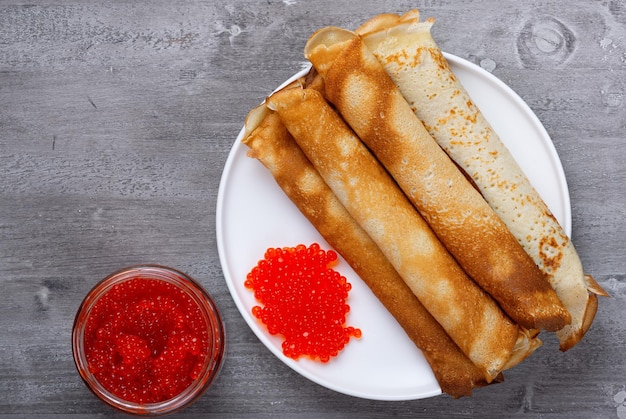 Russische pannenkoeken met rode kaviaar op een grijze tafel