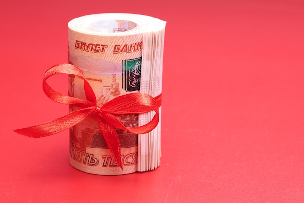 Russische roebels vijfduizend bankbiljetten bundel geld met rood lint op rode achtergrond cadeau concept