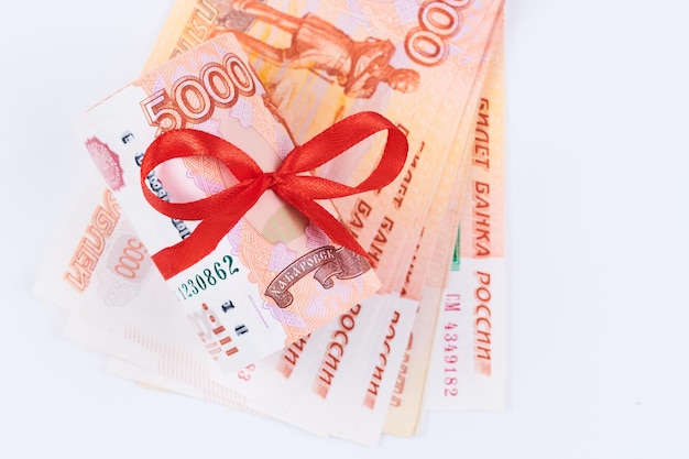 Russische roebels vijfduizend bankbiljetten bundel geld met rood lint op witte achtergrond cadeau concept