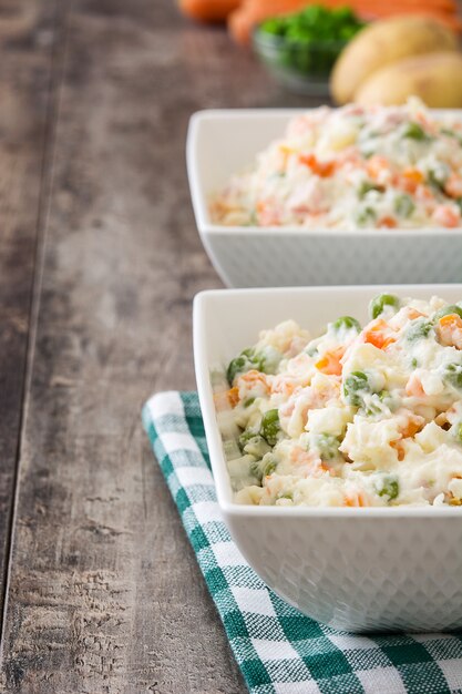 Russische salade in kom op een rustieke houten tafel