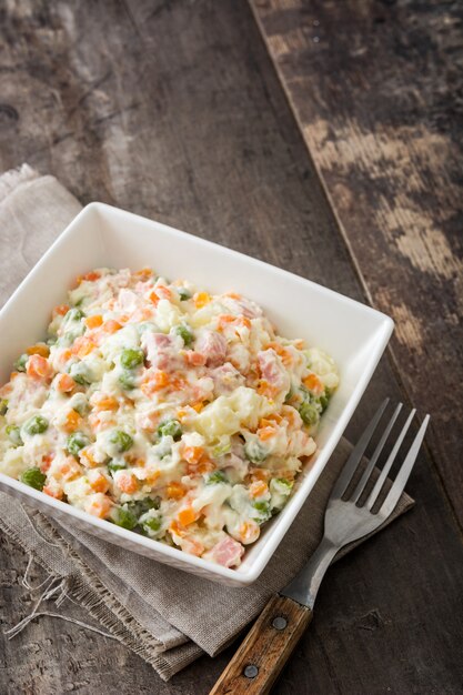 Russische salade in kom op een rustieke houten tafel