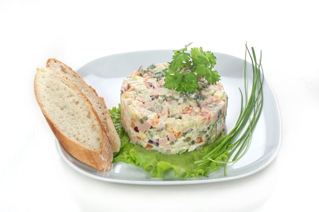 Russische salade op een witte plaat met brood