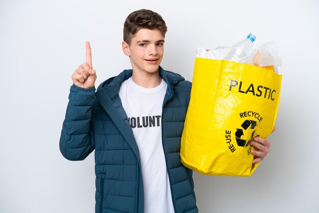 Russische tiener die een zak vol plastic flessen vasthoudt om te recyclen op een witte achtergrond die een vinger laat zien en optilt als teken van het beste