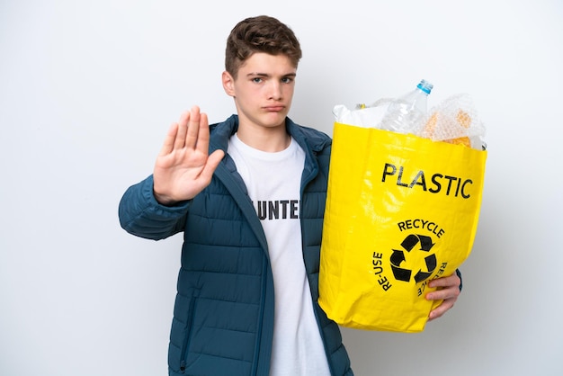 Russische tiener met een zak vol plastic flessen om te recyclen op een witte achtergrond en maakt een stopgebaar