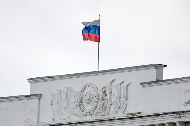 Russische vlag die bovenop het gebouw in de stad Rusland van Moskou zwaait tegen de blauwe lucht en het oude architectuurlandschap van het stalin-tijdperk