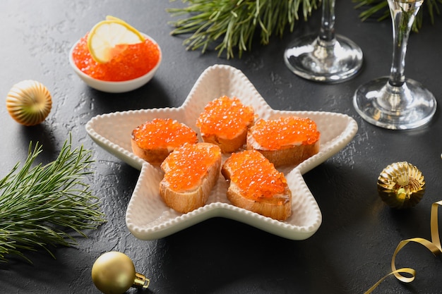 Russische voorgerecht canapé met rode kaviaar op zwarte achtergrond voor Kerstmis.