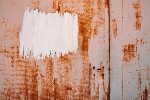 Rust metal surface. Partly rusty background. Rough oxide plate close-up. White painted spot. Hard decay texture. Oxidation of steel. Partially rusted metal panel. Peeling paint.