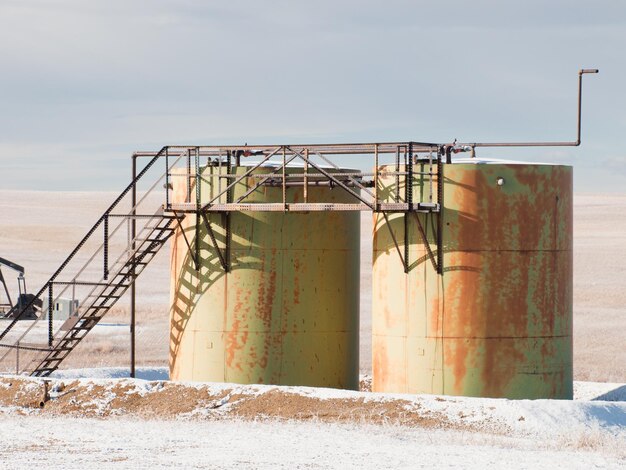 Rusted industrial storage tanks in winter landscape.