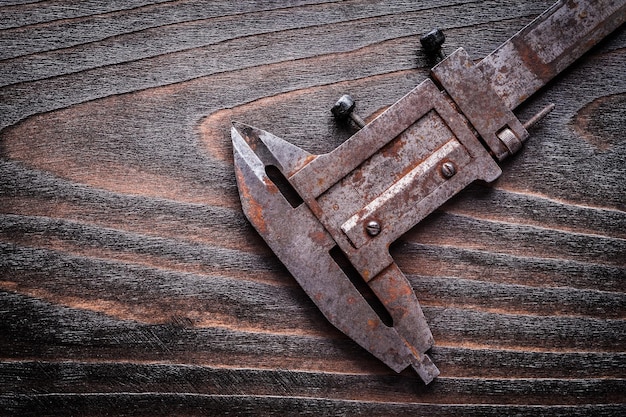 Rusted metal vernier caliper on vintage wooden board construction concept