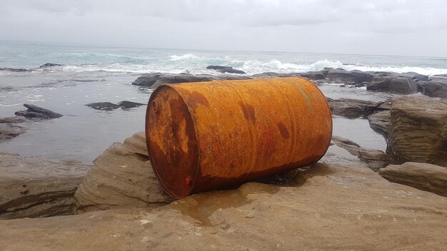 Photo rusted oil drum on beach against sky