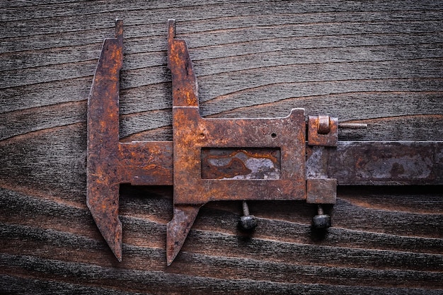 Rusted oldfashioned measuring slide caliper on vintage wooden board construction concept