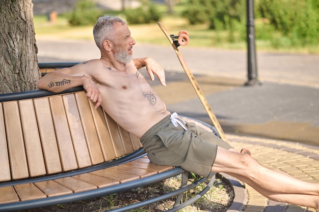 Rusten. Een man die op de bank zit na het sporten in het park