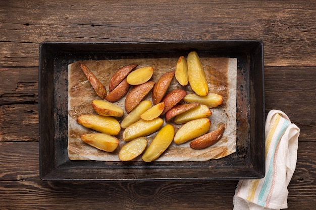 Фото Картофель запеченный по-деревенски в жестяной форме на обеденном столе.
