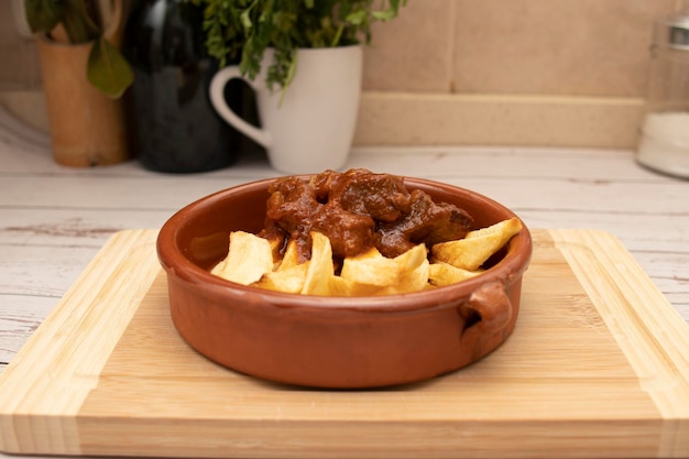 Foto un piatto rustico di argilla con gulasch e patate posto su una tavola di legno concetto di cibi tradizionali