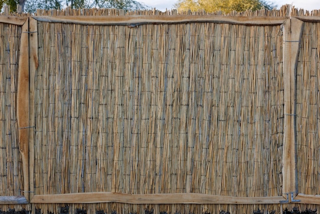 Rustic fence made of wicker straw mat