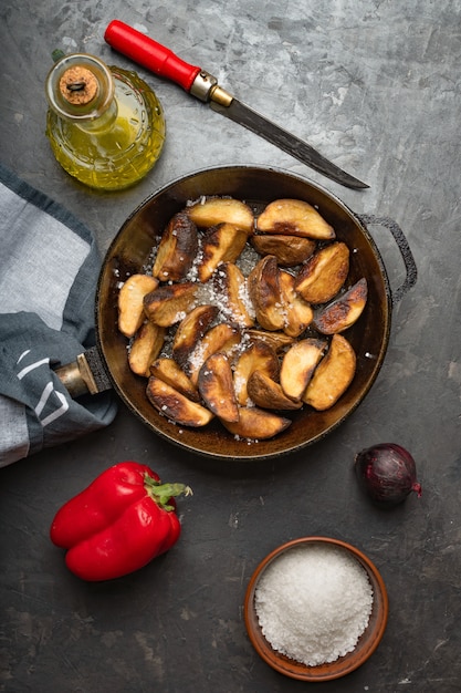 Cibo rustico. patate fritte in padella su un tavolo di cemento scuro. stile rustico.