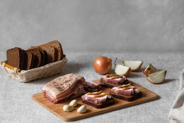 rustic food, ready-made sandwiches of black rye bread and lard with mustard on a linen tablecloth