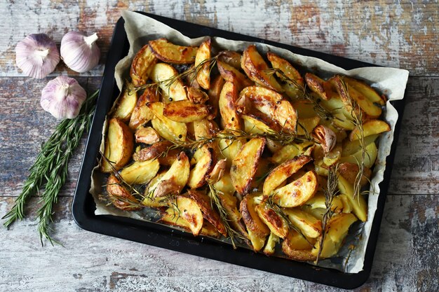 Foto patate al forno dorate rustiche. patate al forno a fette con spezie, aglio e rosmarino.