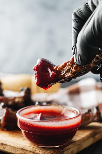 rustic grilled bbq ribs with red sauce pork and beef roasted on charcoal wooden background delicious meal