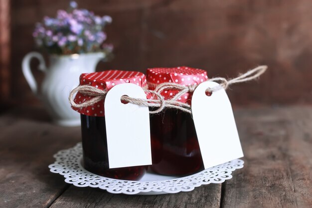 Rustic homemade jam jar wooden background and flower