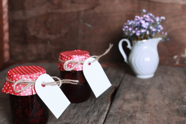 Rustic homemade jam jar wooden background and flower