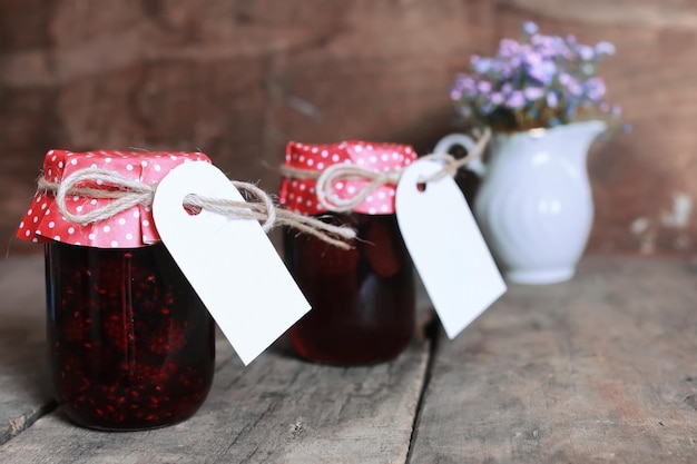 Rustic homemade jam jar wooden background and flower