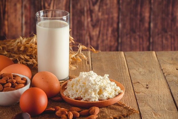 소박한 홈메이드 단백질 균형 잡힌 식단 음식 코티지 치즈 달걀 견과류와 우유는 나무 배경에 있습니다