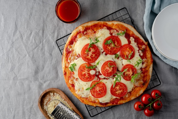 Rustic italian homemade Pizza Dough margherita topped with pizza sauce from canned tomatoes, mozzarella cheese and arugula on dark linen textile tablecloth