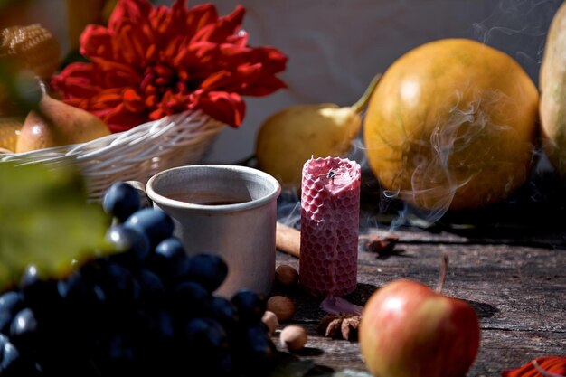 Rustic natural cozy still life of mug of tea fruits hazelnuts and cinnamon sticks Autumn aesthetic concept red georgine Cozy home with warm tea and aromatic candle Thanksgiving Day concept