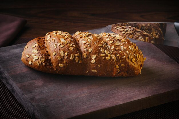 A rustic oat bread on a wooden board on a fine table