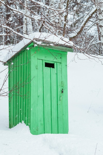 Rustic outdoor wooden toilet in a snowy forest
