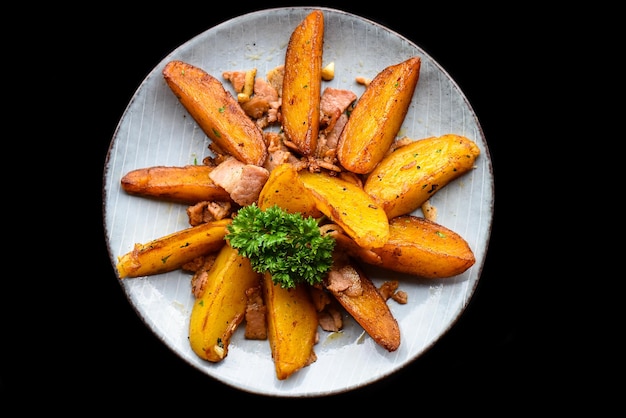 rustic potato wedges with bacon on black background top view