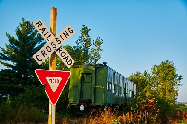 Photo rustic railroad crossing with vintage green train car and yield sign