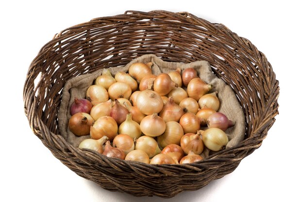 Rustic vine basket filled with yellow onions lying on a linen bag