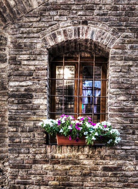 Rustic window with metal grill in a brick wall in San Gimignano Italy